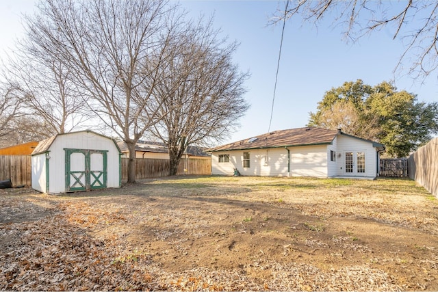 view of yard with french doors, a fenced backyard, an outdoor structure, and a storage shed