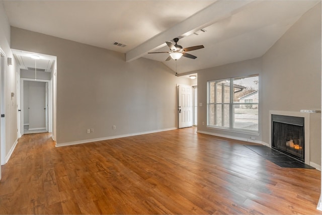 unfurnished living room featuring ceiling fan, wood finished floors, visible vents, a fireplace with flush hearth, and attic access