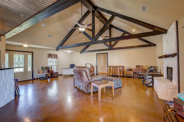 living area featuring high vaulted ceiling, concrete floors, a stone fireplace, and visible vents