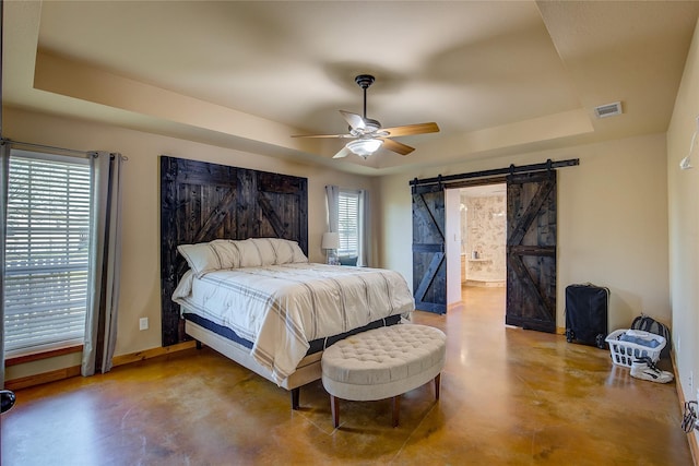 bedroom featuring a barn door, finished concrete floors, a tray ceiling, and visible vents