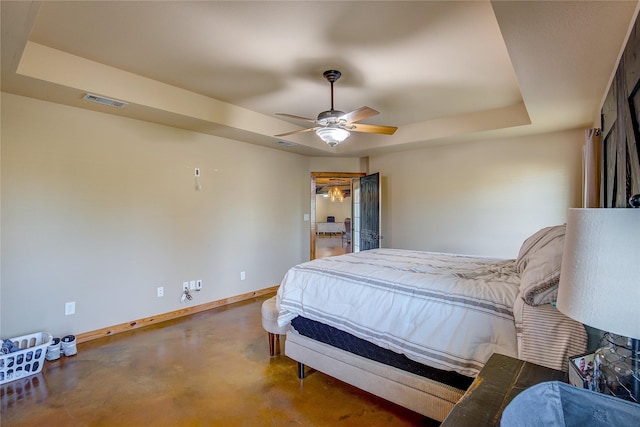 bedroom with visible vents, baseboards, ceiling fan, finished concrete floors, and a tray ceiling