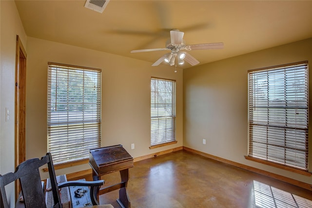 office space featuring baseboards, a ceiling fan, visible vents, and finished concrete floors