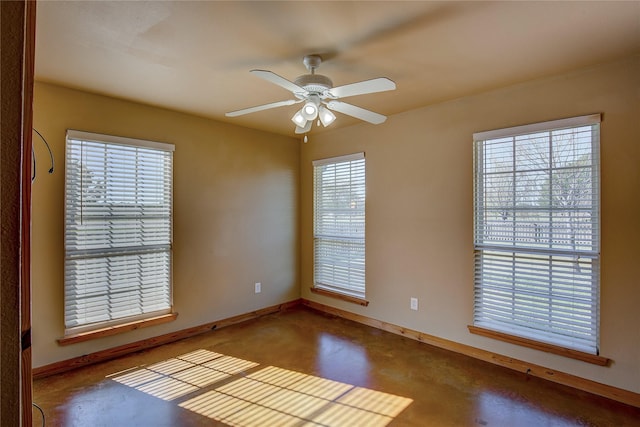 unfurnished room with finished concrete flooring, baseboards, and a ceiling fan