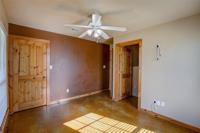 unfurnished room featuring concrete flooring, ceiling fan, visible vents, and baseboards