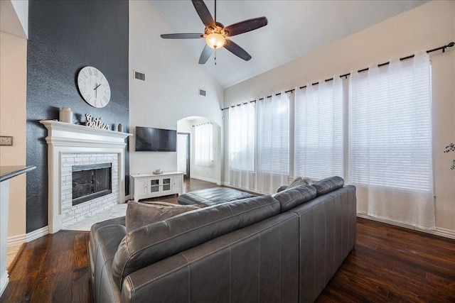 living room featuring a fireplace with flush hearth, a ceiling fan, visible vents, and wood finished floors