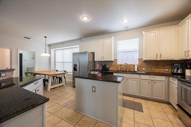 kitchen featuring light tile patterned floors, stainless steel appliances, a sink, a kitchen island, and visible vents