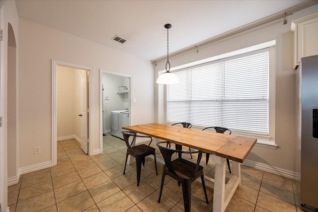 dining area featuring arched walkways, visible vents, light tile patterned flooring, independent washer and dryer, and baseboards