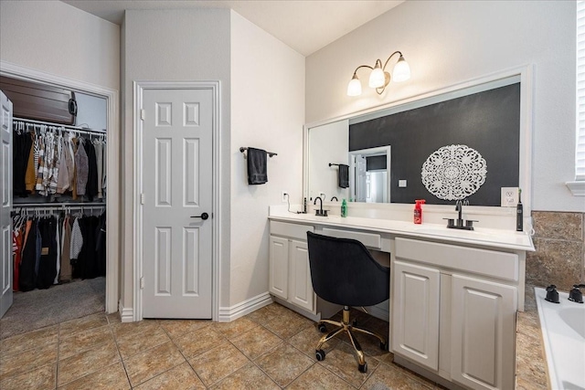 full bathroom with double vanity, tile patterned floors, a spacious closet, a washtub, and a sink