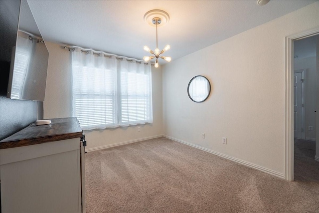 unfurnished dining area featuring baseboards, carpet, and an inviting chandelier