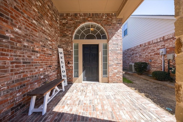 entrance to property featuring cooling unit and brick siding