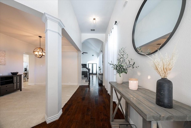 corridor featuring decorative columns, visible vents, stairway, an inviting chandelier, and wood finished floors