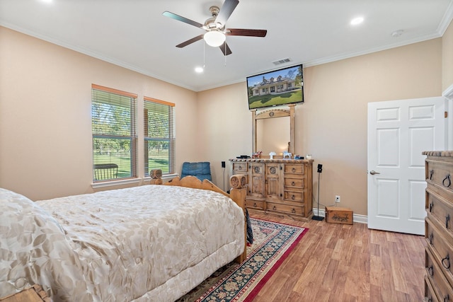 bedroom featuring baseboards, light wood finished floors, visible vents, and crown molding