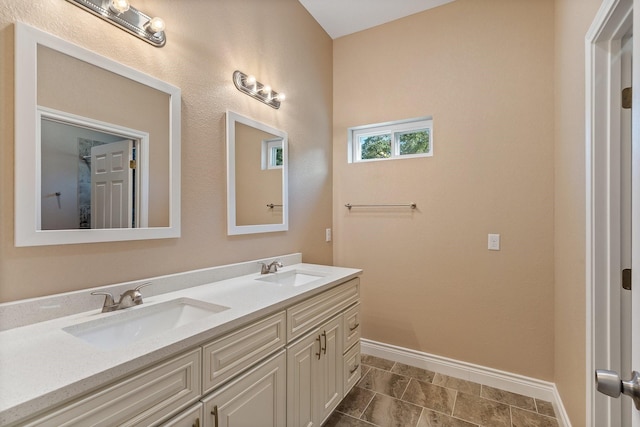 bathroom with a sink, baseboards, and double vanity