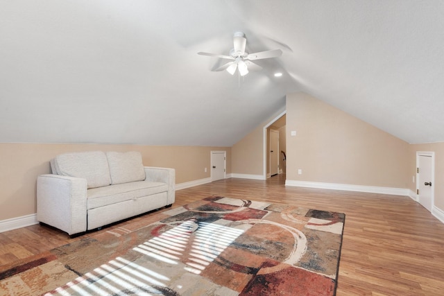 living room featuring lofted ceiling, wood finished floors, and baseboards