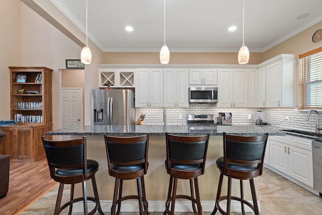 kitchen with ornamental molding, appliances with stainless steel finishes, a sink, and white cabinetry