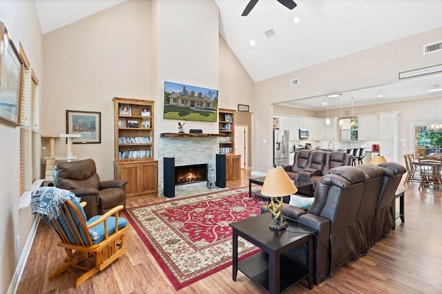 living area with a ceiling fan, visible vents, a fireplace, and light wood-style flooring