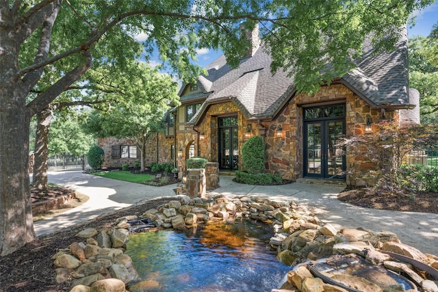 1717 Buckingham Dr, Keller, TX 76262 - english style home with french doors, stone siding, a small pond, and roof with shingles