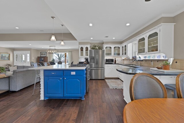 kitchen with appliances with stainless steel finishes, visible vents, a sink, and glass insert cabinets