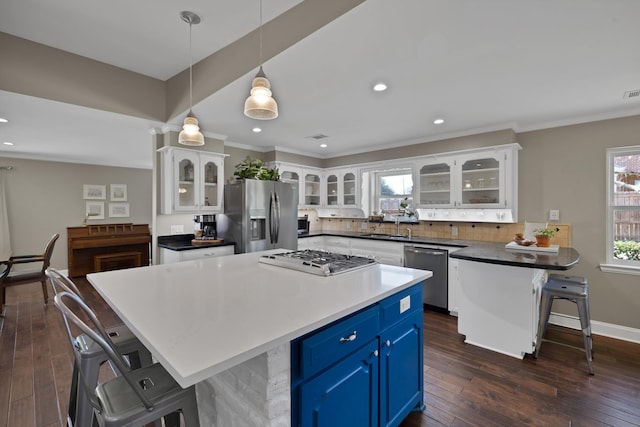 kitchen featuring blue cabinets, white cabinetry, appliances with stainless steel finishes, and a breakfast bar