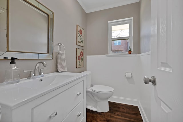 bathroom featuring toilet, ornamental molding, vanity, wood finished floors, and baseboards