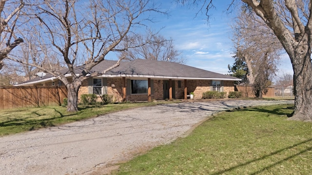 single story home with a front yard, brick siding, driveway, and fence