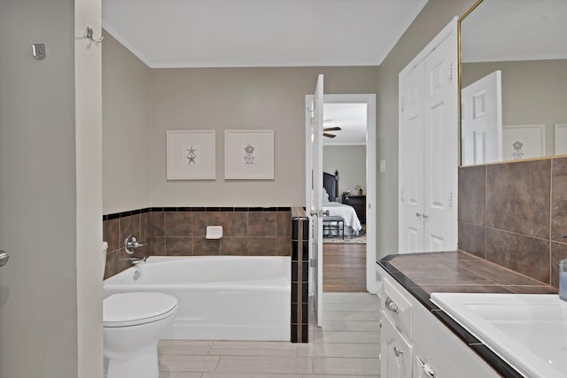 full bath featuring crown molding, tile walls, toilet, vanity, and a bath