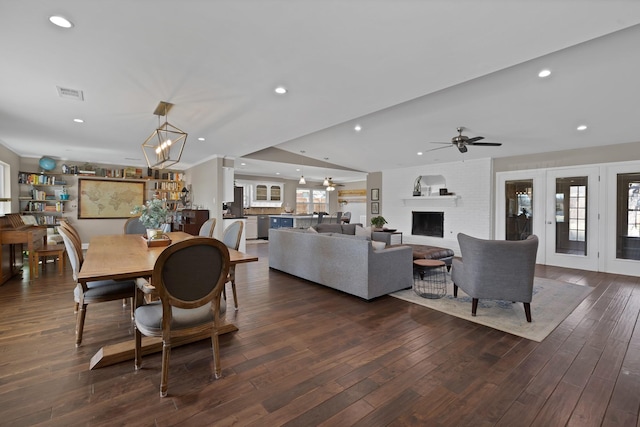 dining area featuring dark wood-style floors, a brick fireplace, visible vents, and recessed lighting