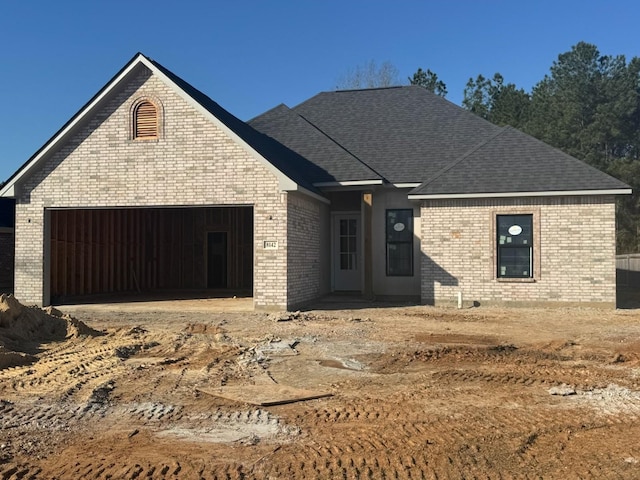 view of front of property featuring brick siding, roof with shingles, and an attached garage