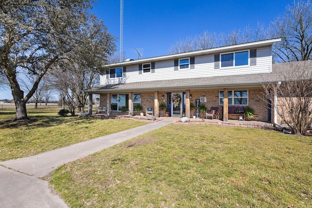 view of front of home featuring a front yard, a porch, and brick siding