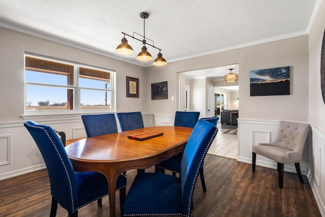 dining space with a decorative wall, wainscoting, wood finished floors, and crown molding