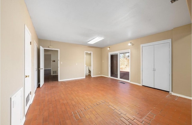 unfurnished bedroom featuring brick floor, access to outside, visible vents, and baseboards