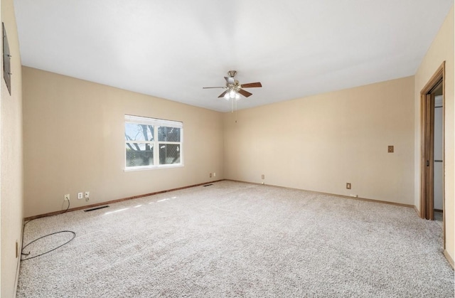 carpeted spare room featuring visible vents, ceiling fan, and baseboards