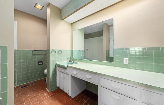 full bath featuring visible vents, wainscoting, toilet, vanity, and tile walls