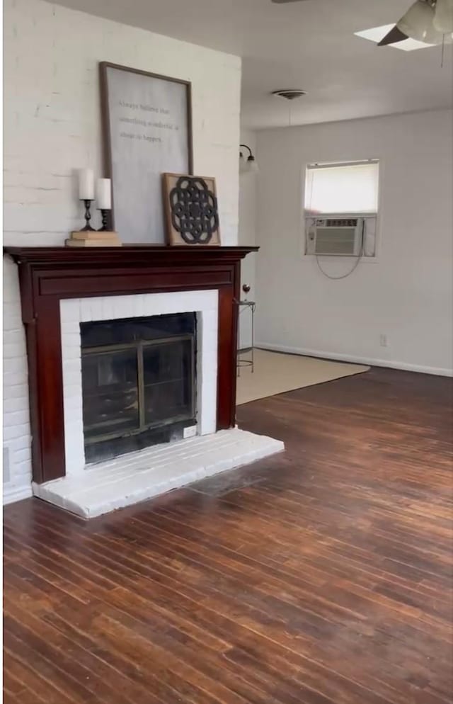 unfurnished living room featuring ceiling fan, a brick fireplace, wood finished floors, and cooling unit