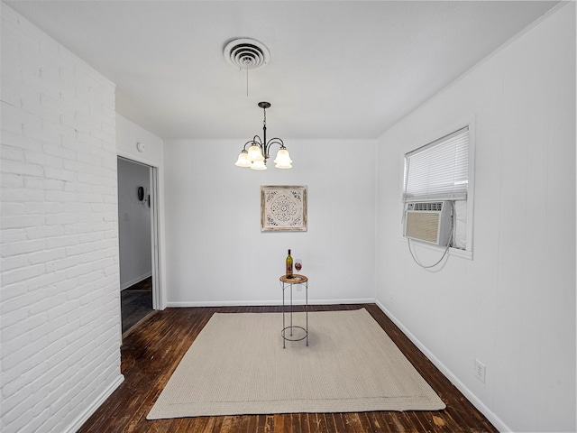 unfurnished dining area featuring cooling unit, brick wall, visible vents, dark wood finished floors, and an inviting chandelier