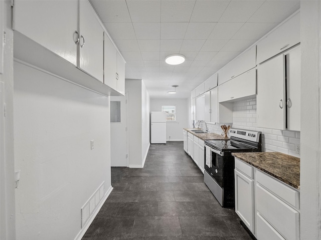 kitchen featuring visible vents, electric stove, backsplash, freestanding refrigerator, and a sink