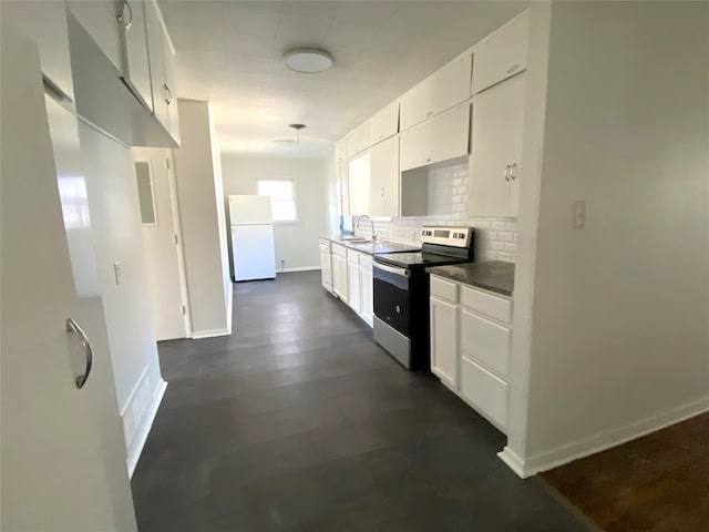 kitchen with a sink, white cabinetry, freestanding refrigerator, decorative backsplash, and stainless steel electric range oven