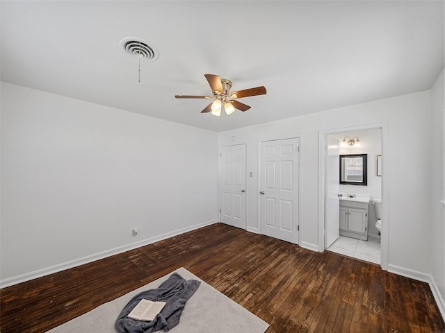 unfurnished bedroom featuring visible vents, connected bathroom, baseboards, and hardwood / wood-style flooring