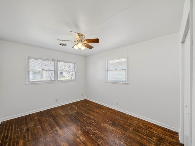 spare room with ceiling fan, dark wood finished floors, visible vents, and baseboards