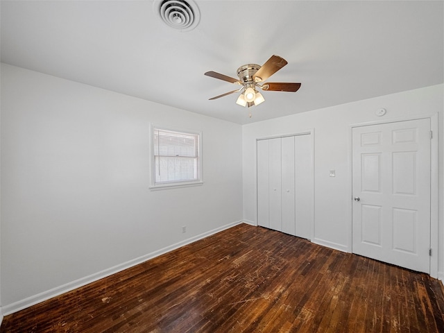 unfurnished bedroom with dark wood-style floors, baseboards, visible vents, and a closet