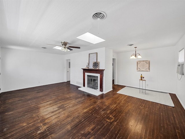 unfurnished living room with a skylight, visible vents, dark wood-type flooring, a ceiling fan, and a brick fireplace