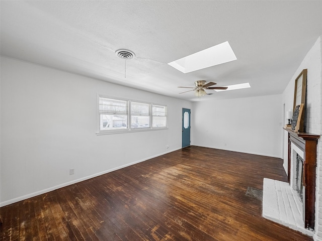 unfurnished living room with a skylight, a fireplace, visible vents, and wood-type flooring