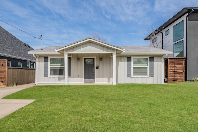 view of front of home with board and batten siding, a front yard, and fence