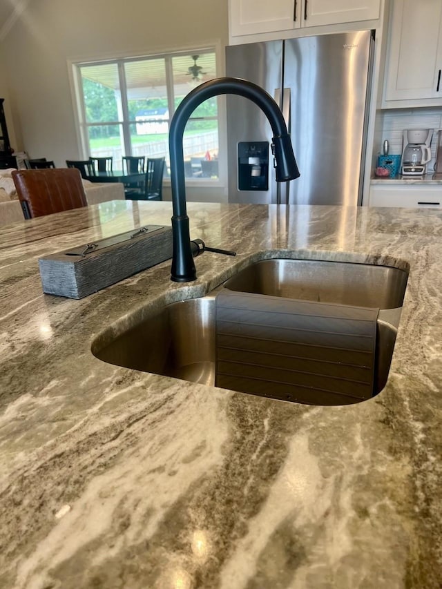 room details featuring stone counters, white cabinets, and a sink