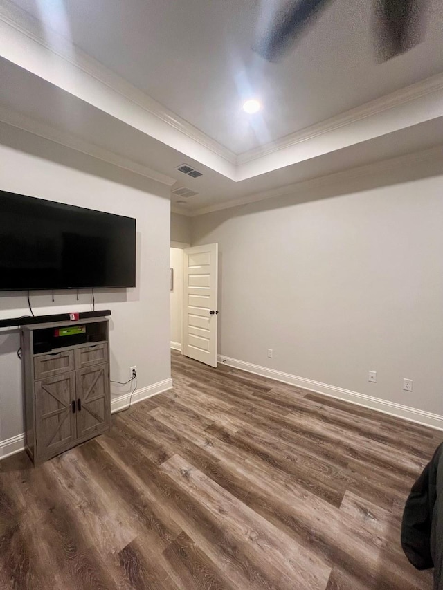 unfurnished living room featuring a tray ceiling, crown molding, visible vents, dark wood-type flooring, and baseboards