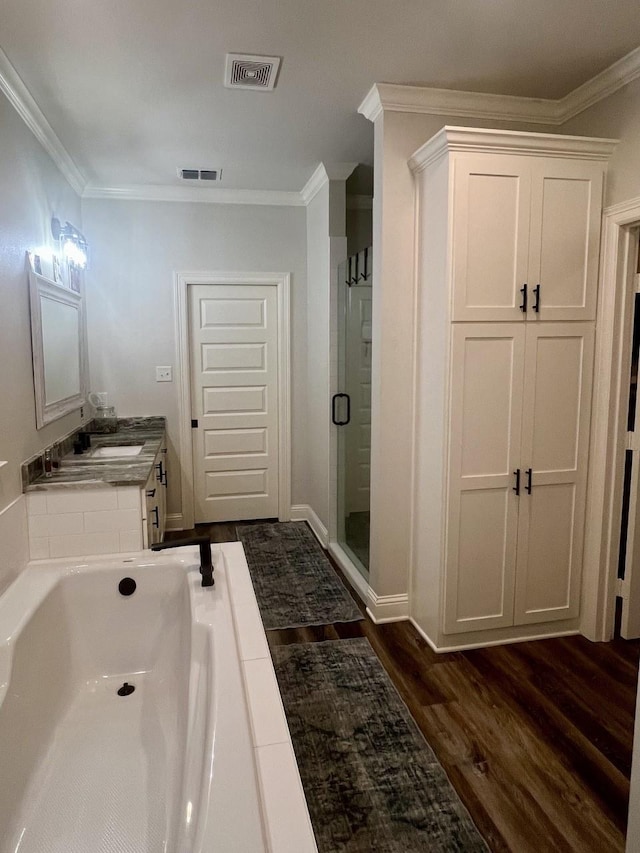 bathroom featuring a garden tub, wood finished floors, visible vents, ornamental molding, and a shower stall