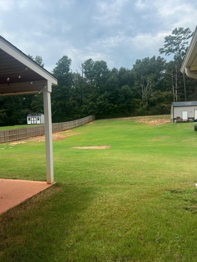 view of yard featuring a storage unit, an outdoor structure, and fence