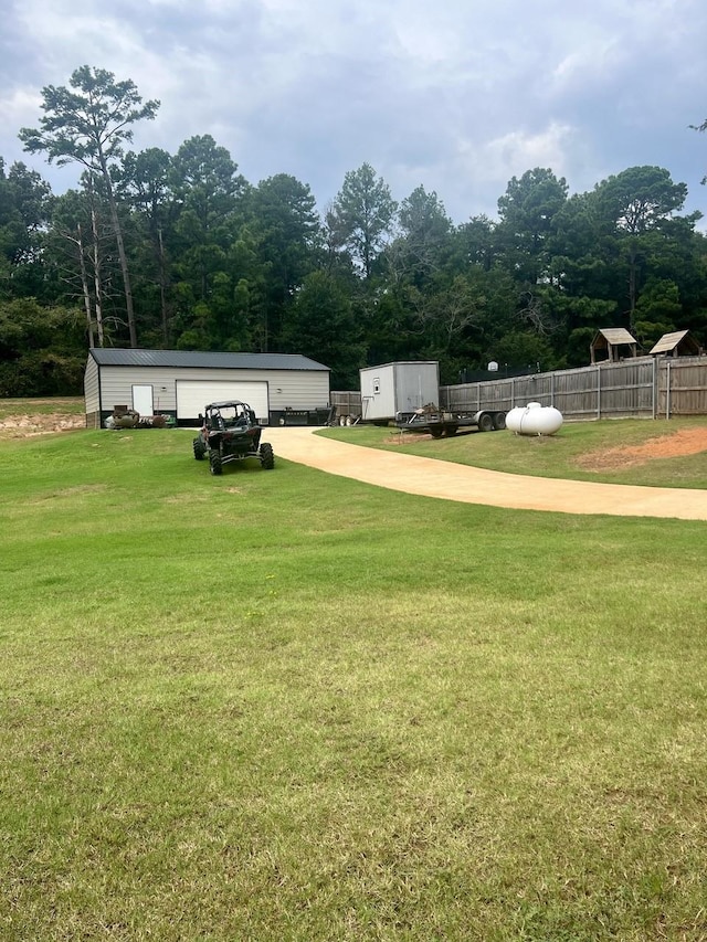 view of yard featuring a detached garage, an outdoor structure, and fence