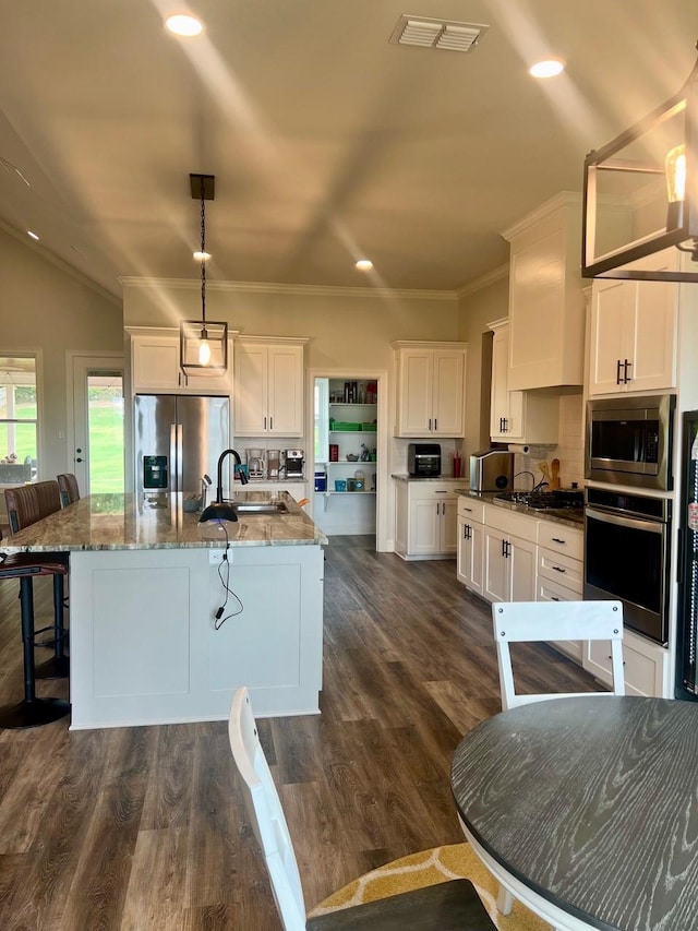 kitchen with a sink, visible vents, white cabinetry, appliances with stainless steel finishes, and a kitchen bar