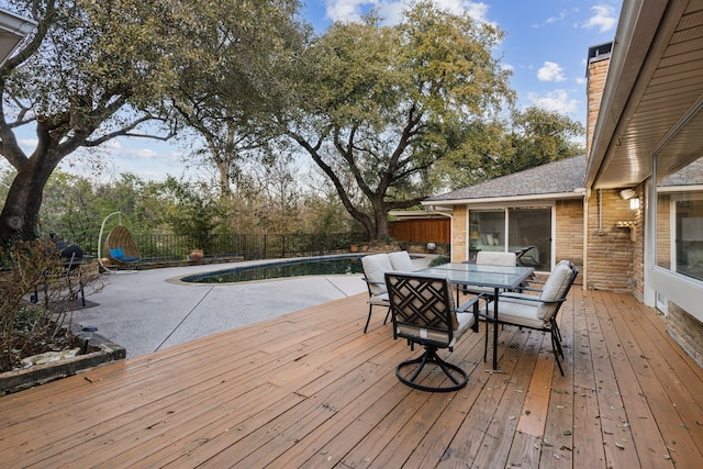 wooden terrace with outdoor dining space, a fenced backyard, and a fenced in pool